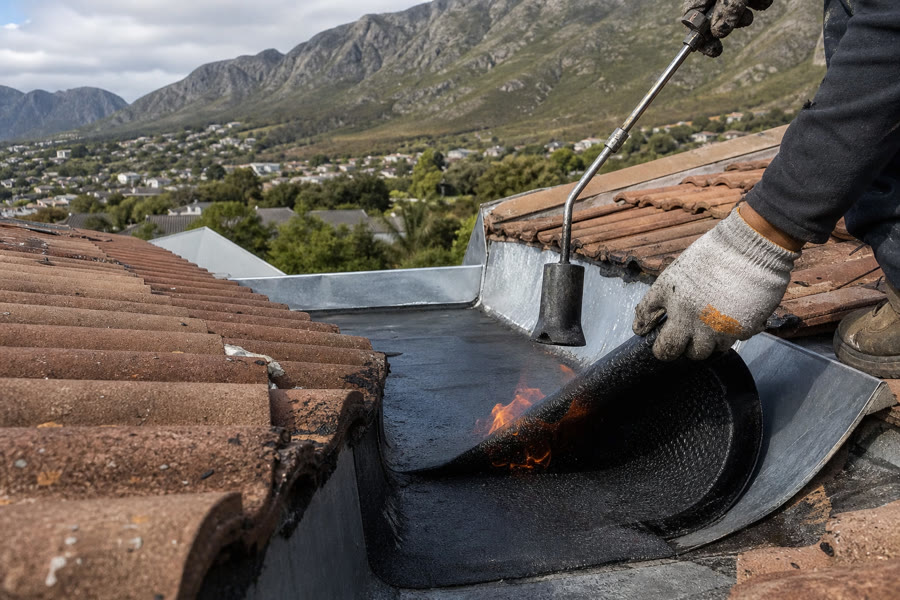 Torch-on membrane being bonded into a tiled-roof box gutter in Somerset West.